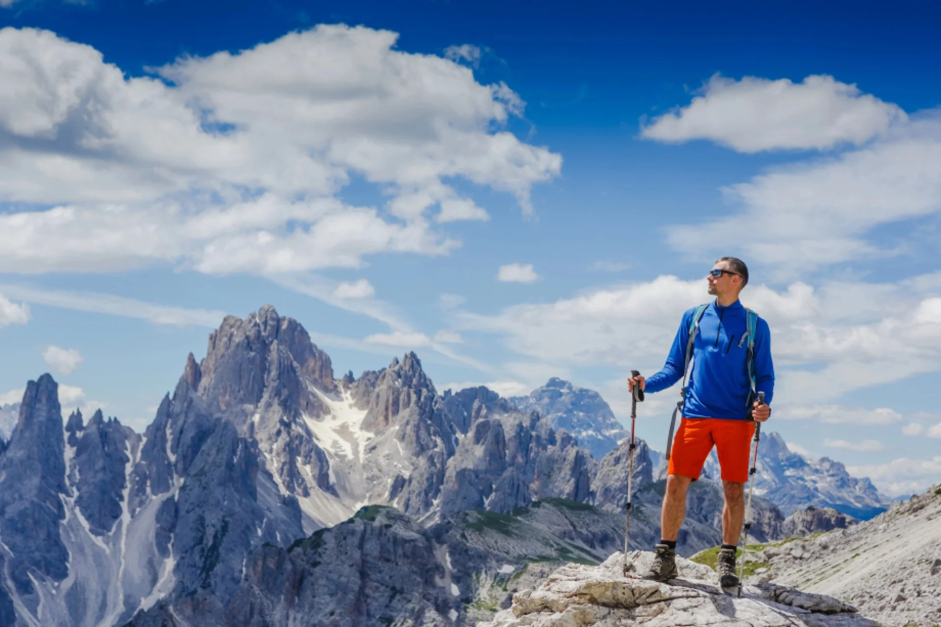 Man with hiking poles looking at Dolomite mountain scape