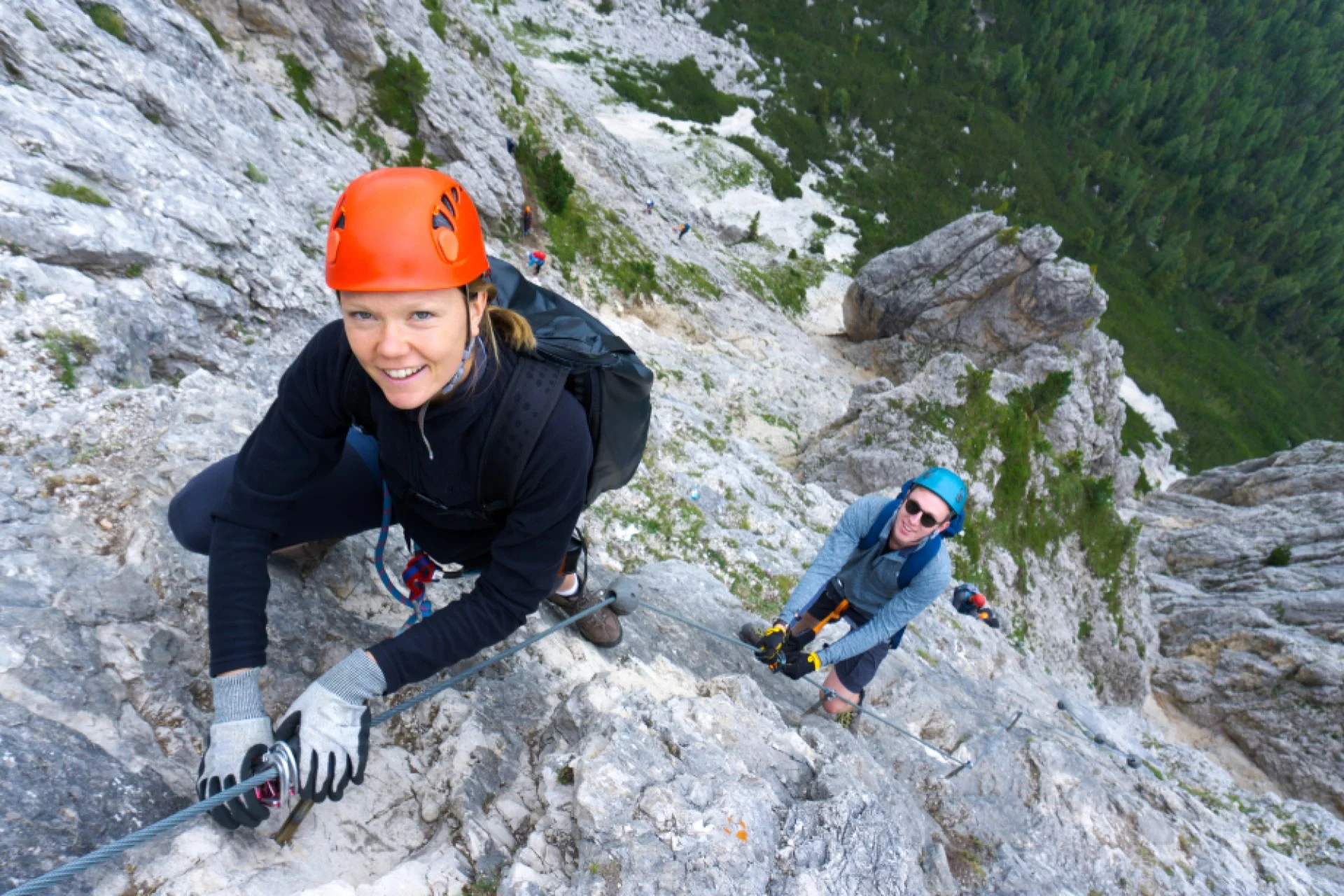 Two people with helmets on via ferrata