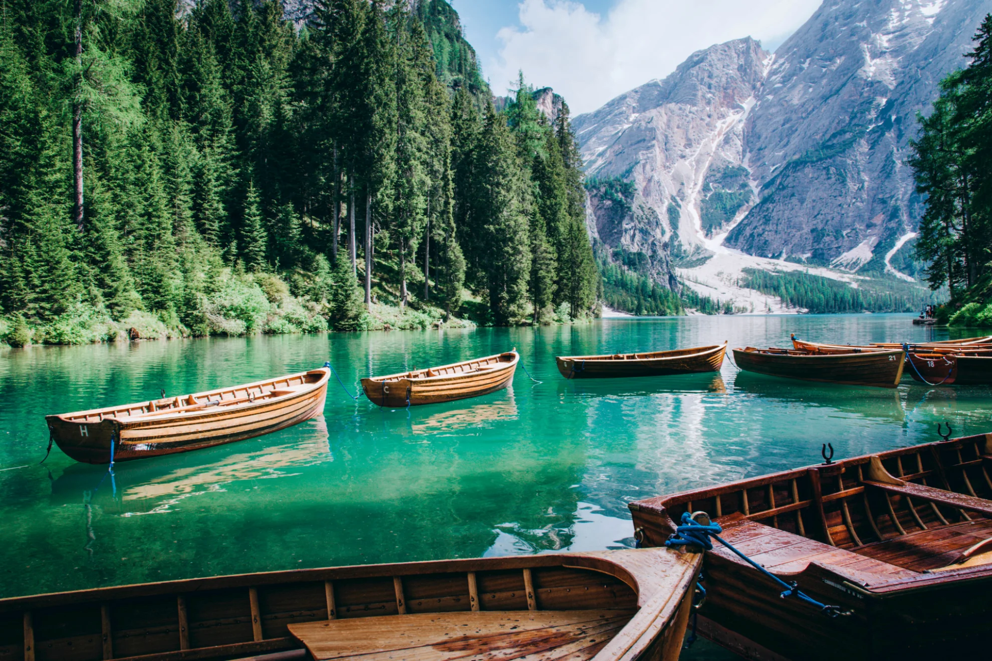 Wooden tour boats on Lago di Braies with Sasso del Signore mountain in the background.