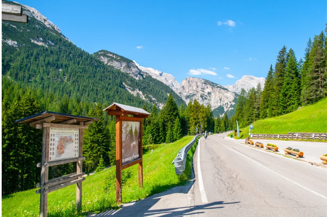 Dolomites road with mountain views and tourist signboards.